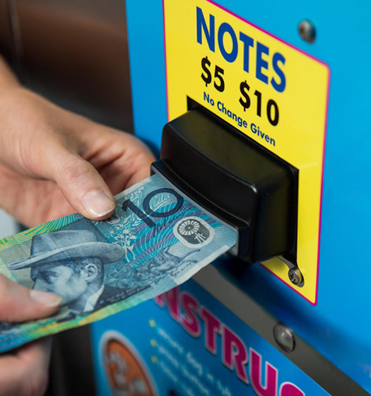 Customer paying with a $10 note at a self-serve coin dog wash